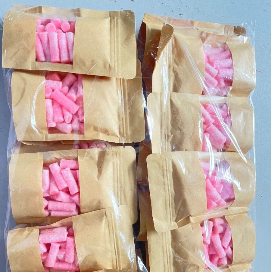 Pink firelighter pellets in kraft paper retail bags with a clear window